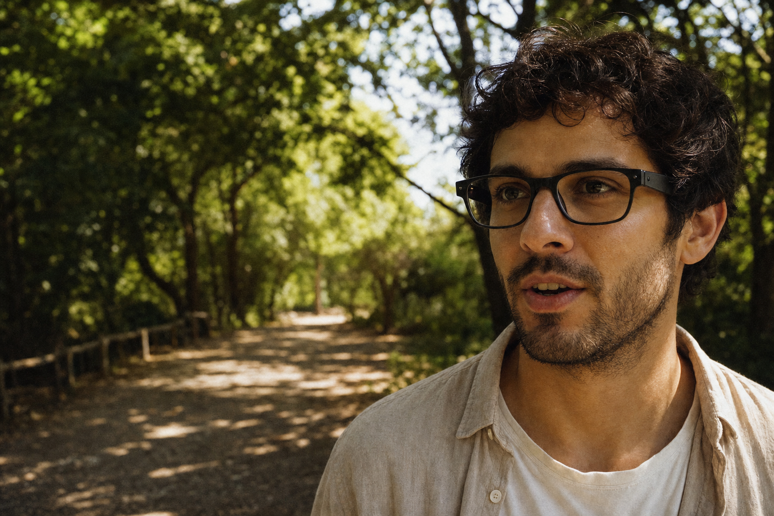 A person walking through a sunlit park wearing lightweight smart glasses.